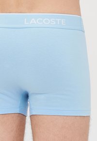 Bañadores de algodón azul claro con una cintura impresa con logo. Presentan un ajuste ceñido y una textura suave, con un diseño minimalista y sin patrones.