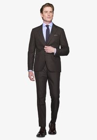 Mørkebrun skræddersyet jakkesæt med notch-lapel, matchende bukser og en lys blå skjorte. Accentueret med et mønstret slips og polerede sko.