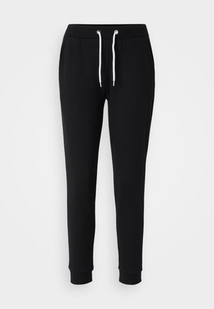 Black sweatpants with a drawstring waist, white cord accents, tapered legs, and ribbed cuffs. Made from soft, comfortable fabric.