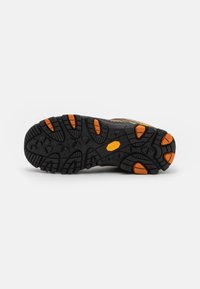 Semelle d'une chaussure de randonnée en caoutchouc noir durable avec des profondeurs de relief et des accents orange. Surface texturée pour la traction et la stabilité.