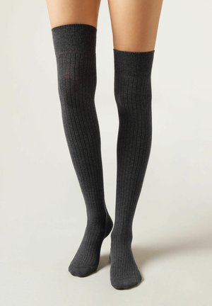 Calcetines hasta la rodilla en gris oscuro, con textura acanalada, fabricados en material suave. Acabado liso con parte superior elástica para un ajuste ceñido.