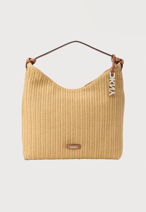 Sac à épaule tissé beige avec anse marron, plaque logo DKNY et breloque argentée suspendue à la bandoulière.