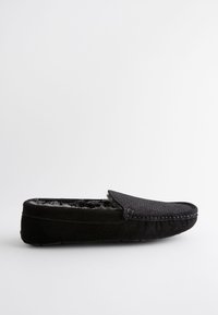 Svart mockamosaik med texturerad ovandel, mjuk innerfoder och flat sula. Har en slip-on-design och minimala sömmar.