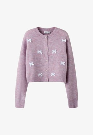 Różowy krótki kardigan wykonany z miękkiego materiału, z białymi wstążeczkami w kształcie kokardek oraz perłowymi guzikami z przodu. Fason ze ściągaczami przy rękawach i u dołu.