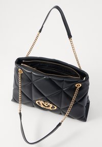 Μαύρη καπιτονέ τσάντα χειρός με χρυσό λογότυπο. Διαθέτει αλυσίδα για χερούλι και λεία δερμάτινη υφή, αναδεικνύοντας μια δομημένη ορθογώνια μορφή.