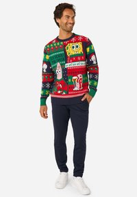 Kootud pühadekohtumine, kus on värvikad tegelased, sealhulgas multifilmist sõrmus, pidulike mustritega tumesinisel taustal.