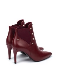 Botas de tobillo burdeos con punta afilada, hechas de cuero y tela elástica. Presentan botones dorados a lo largo del costado y tacones altos de aguja.