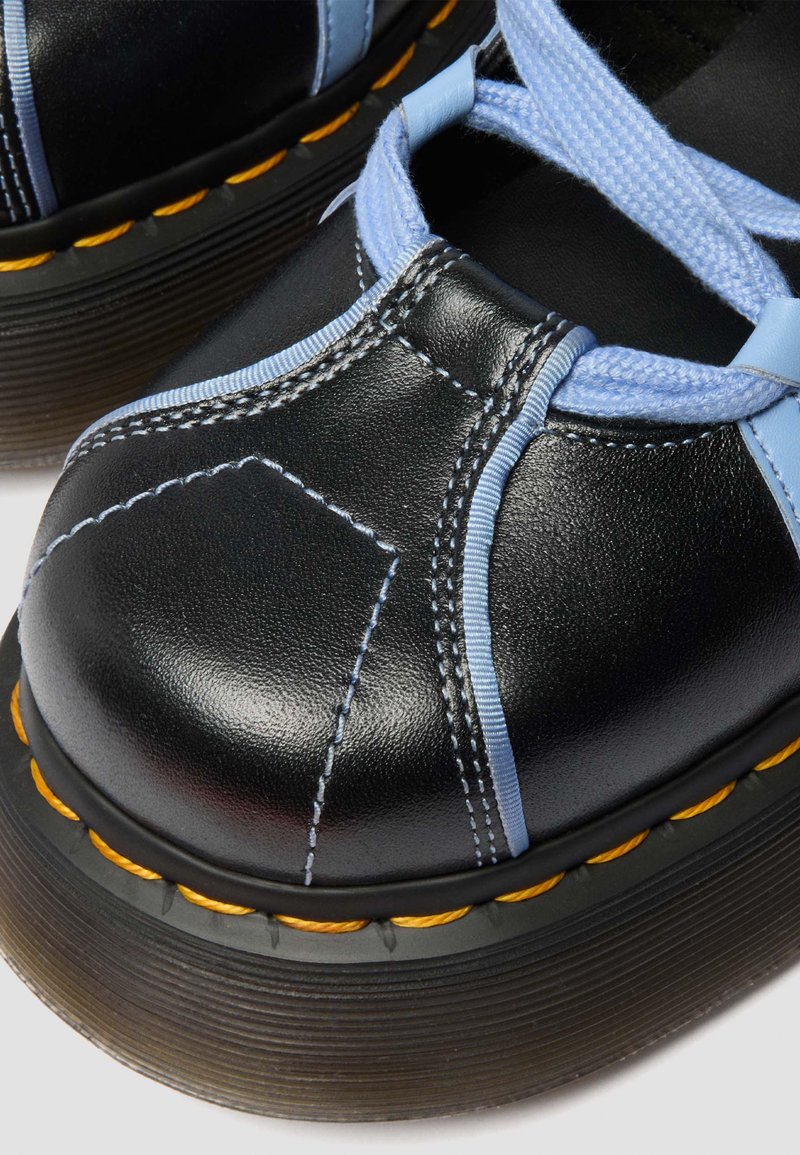 Black leather shoes with thick soles, light blue stitching and laces, and yellow stitching detail around the sole edges.