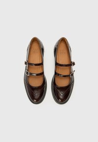 Brown leather shoes with two buckle straps, rounded toe, and decorative perforations. Smooth, shiny texture with a flat black sole.