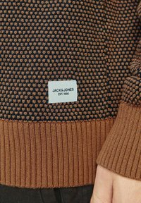 Pulover tricotat cu un design texturat, având culori bleu închis și maro, manșete dintr-un material cu nervuri și un eticheta Jack & Jones pe tiv.