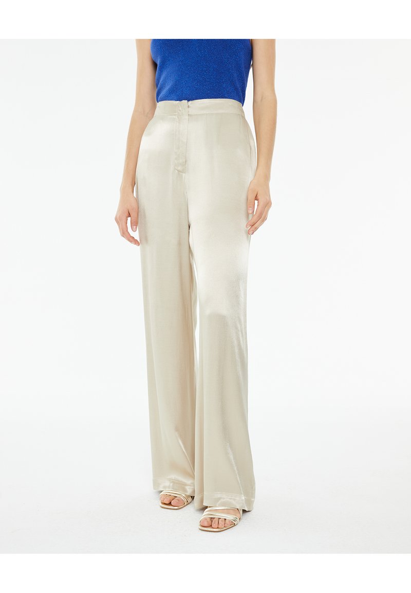 Pantaloni a gamba larga in satin beige chiaro con una superficie liscia e vita alta, dotati di chiusura frontale e tasche laterali.
