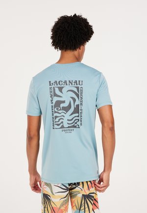 Lyseblå kortærmet t-shirt med en tekstureret tryk, der har sorte abstrakte mønstre og teksten "LACANAU FAVOURITE PLACES" på ryggen.