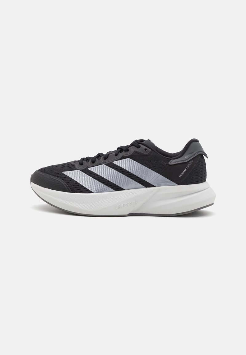 Chaussure de course athlétique noire et blanche avec trois bandes blanches, semelle amortie et design à lacets, vue de côté extérieur.