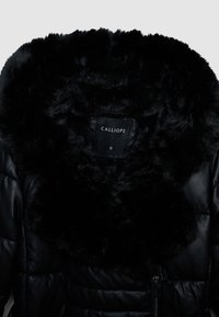 Giacca a piumino nera con colletto in ecopelliccia. Presenta un design trapuntato, chiusura con zip e un'etichetta con la scritta "CALLIOPE", taglia small.
