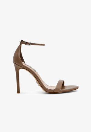 Sandalo marrone con tacco alto, cinturino sottile alla caviglia con fibbia, punta aperta e tacco a stiletto sottile su sfondo bianco.