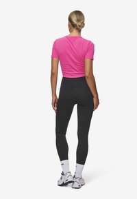 Aansluitend roze cropped t-shirt, gecombineerd met hooggewaisted zwarte leggings. Inclusief witte sokken en sportschoenen met een chunky ontwerp.