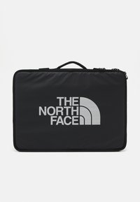 Black fabric carrying case with a silver "THE NORTH FACE" logo and curved design. Features a top handle and sturdy zipper closure.