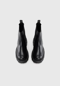 Botas de tornozelo em couro preto com um acabamento suave, costura subtil, painéis elásticos para fácil colocação e sola espessa e resistente.