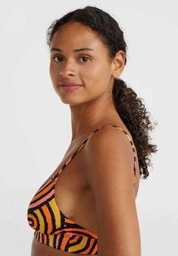 Multicolored bikini top featuring orange, black, and pink spiral patterns, with thin straps and an open side design for a modern look.
