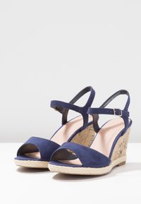 Námořnické modré semišové wedge sandály s otevřenou špičkou, kotníkovým páskem a béžovou pletenou platformou ve stylu juty, se strukturovaným korkovým povrchem.