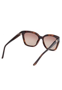 Lunettes de soleil écaille de tortue avec des montures surdimensionnées, des verres dégradés et des détails en métal sur les branches. Fini élégant et lisse avec des branches courbées.