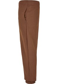 Bruine sweatpants van zacht materiaal, met een taps toelopend ontwerp, elastische tailleband en zijzakken. Boorden bij de enkel.