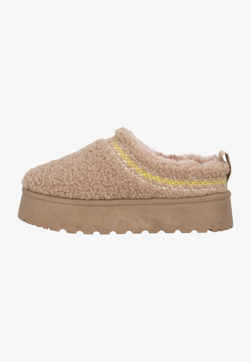 Zapato beige de tipo slip-on con una textura suave, que presenta una suela gruesa y un detalle de costura amarilla a lo largo del borde superior.
