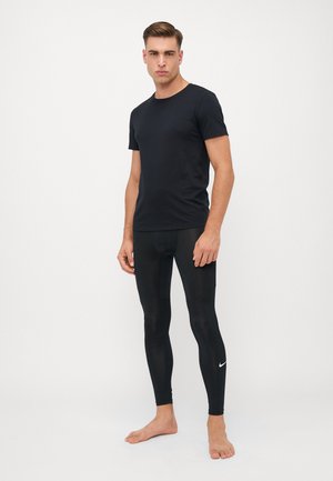 Juodas apvalios kaklo marškinėliai, derinami su juodomis prigludusiomis leggingais. Leggingai turi mažą baltą Nike logotipą apatinėje kojoje.