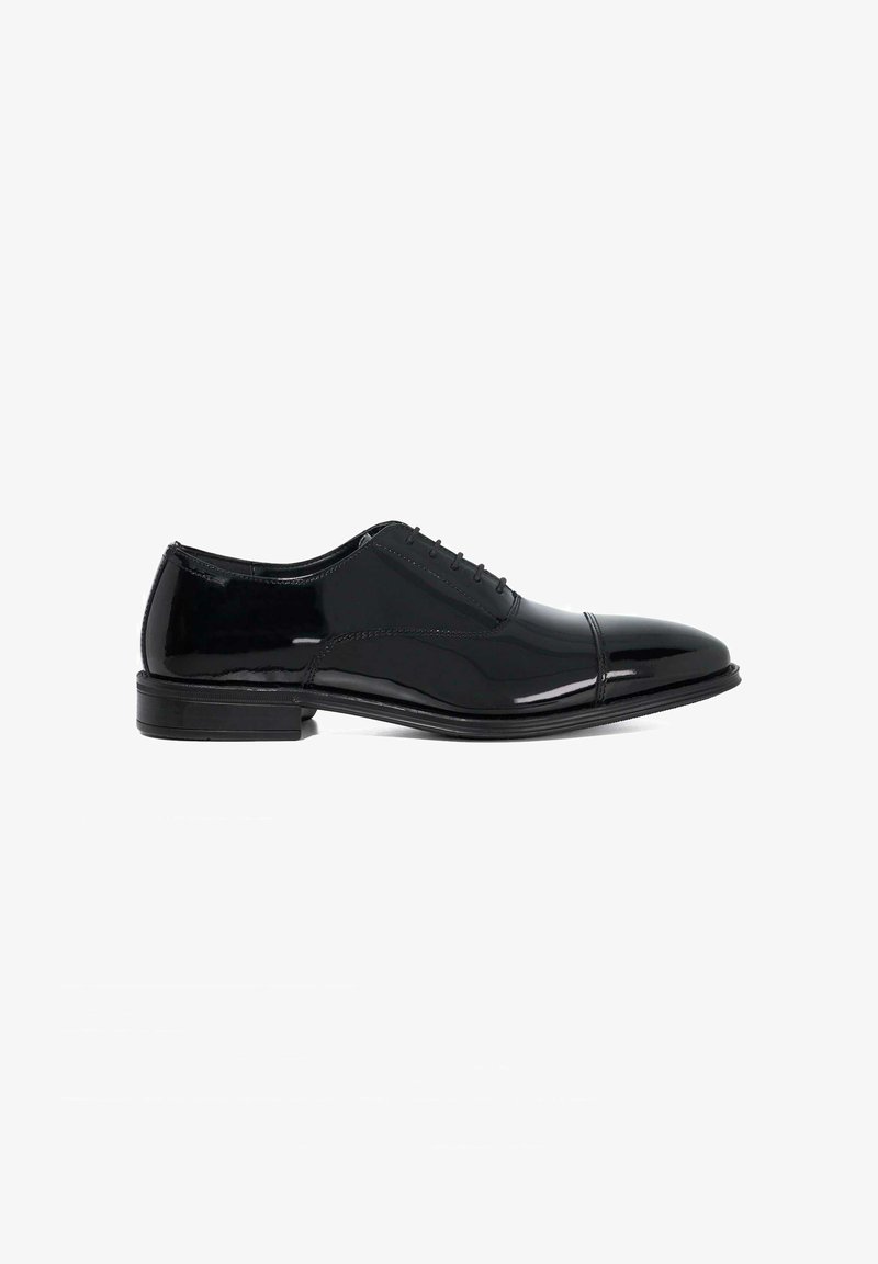 Black patent leather dress shoe with a rounded toe, closed lacing, and a low stacked heel. Features subtle stitching and a glossy finish.