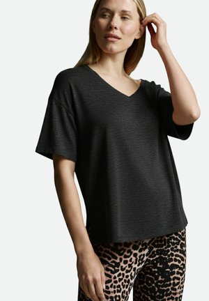 Schwarzes Kurzarm-V-Ausschnitt-T-Shirt aus strukturiertem Stoff, kombiniert mit enganliegenden Leggings im pink-schwarzen Leopardenmuster.