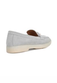 Gray suede loafer with a flat, light-colored sole. Features a simple design with stitched detailing and a slip-on silhouette.