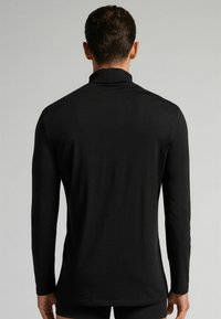 Schwarzes Langarmshirt mit hohem Kragen, aus glattem Stoff gefertigt, mit minimalen Nähten und einer figurbetonten Passform.