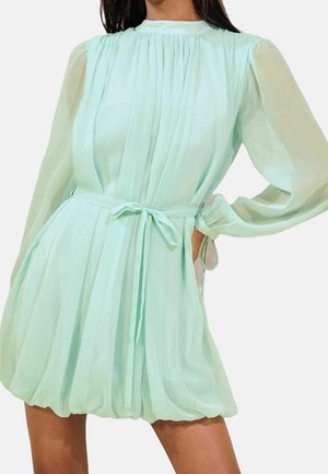 Vestido verde menta con diseño plisado, mangas largas y transparentes, cintura ajustada con un lazo y falda acampanada. Tejido ligero.