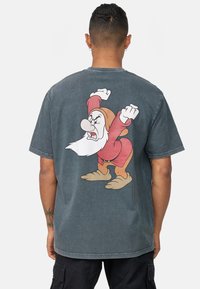 Camiseta de algodón gris grafito con una gran imagen impresa de un personaje enano enojado en la parte posterior. Mangas cortas y corte relajado.