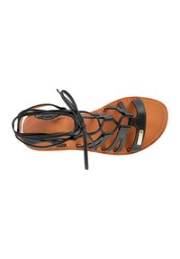 Zwarte leren sandal met gekruiste banden, platte bruine zool en vetersluiting. Heeft een subtiel logo aan de zijkant voor branding.