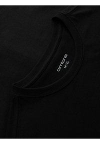 Sorte bomulds T-shirt med rund hals. Har synlige sting og en etikette med teksten "ombre" og størrelse M. Glat tekstur.