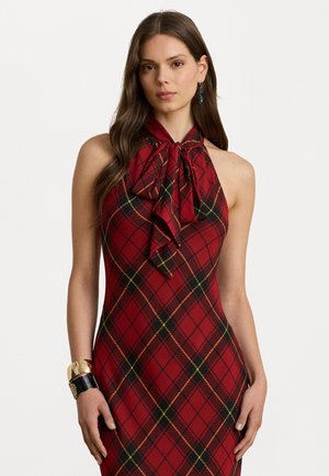 Abito halter a quadri rossi con collo a fiocco, silhouette aderente e linee gialle e verdi in contrasto; accessorized con un bracciale dorato e nero.