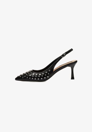 Zapato de tacón tipo slingback negro con punta afilada. Presenta acentos de tachuelas plateadas y un tacón delgado. Fabricado en cuero liso y brillante.