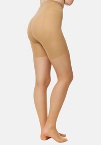 Beige shapewear shorts fremstillet af glat, elastisk materiale med en høj talje, der når til midt på låret, og som har et sømløst design.