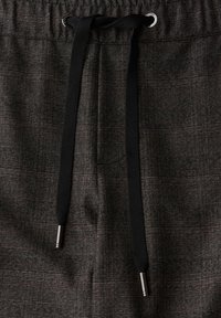 Grau gemusterte Stoffhosen mit einem Zugbandverschluss, ausgestattet mit schwarzen Schnüren und silbernen Metallspitzen zur Anpassung.
