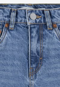 Blue denim jeans with a faded texture, featuring contrasting orange stitching, copper rivets, and a button closure at the waistband.