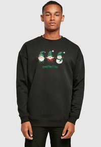 Sort sweatshirt med et broderet design af tre festlige figurer: to skægede personer og en snemand, med grønne accenter og tekst.