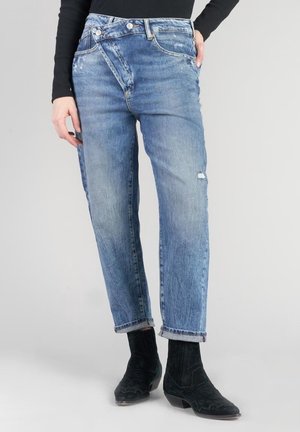 Vaqueros de mezclilla azul con un corte relajado, con un acabado ligeramente desgastado, cinco bolsillos y un diseño de cinturilla asimétrico único.