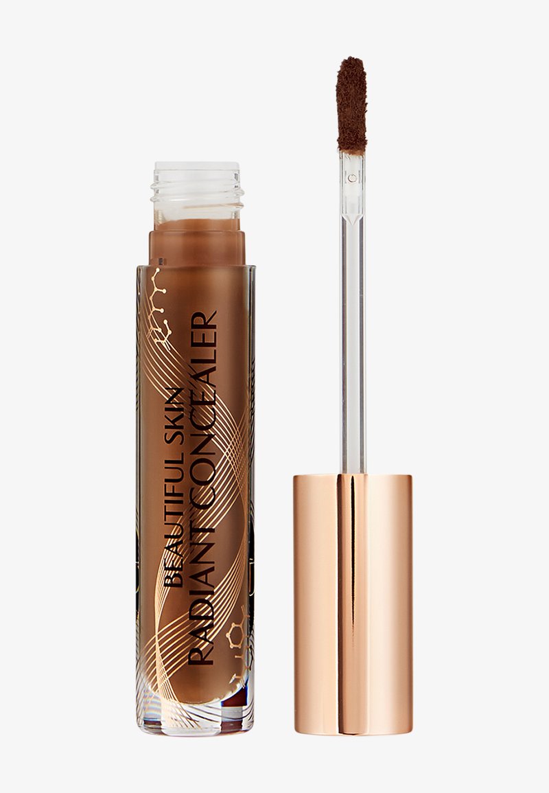 Tube transparent de correcteur liquide marron moyen étiqueté « Beautiful Skin Radiant Concealer » avec un capuchon rose doré et une baguette applicatrice.