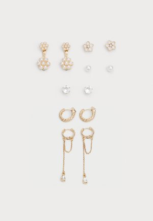 L'ensemble de boucles d'oreilles en ton or présente des motifs floraux, des accents en perles et des clous ronds. Les styles incluent des créoles avec chaînes et détails décoratifs.