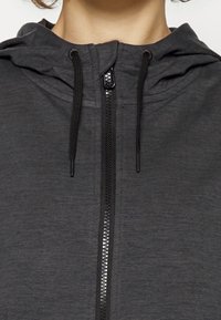 Mörkgrå zip-up hoodie med en slät yta, utrustad med huva med dragsko och svarta dragkedjedetaljer. Minimalistisk design utan synliga mönster.