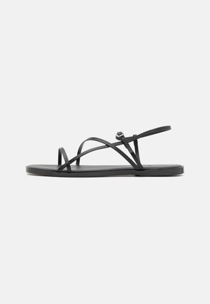 Schwarze flache Sandalen mit dünnen, kreuzförmig verlaufenden Riemen, offener Zehenpartie und minimalistischem Schuhsohle. Verfügt über eine kleine Schnallen-Detail zur Anpassung.