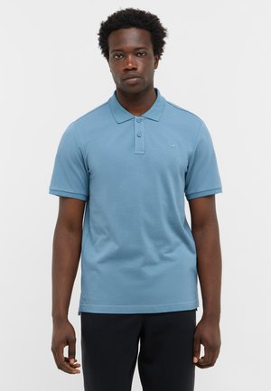 Jasnoniebieska koszulka polo z teksturowanej tkaniny, z kołnierzykiem, trzema guzikami i krótkimi rękawami. Małe logo na piersi.