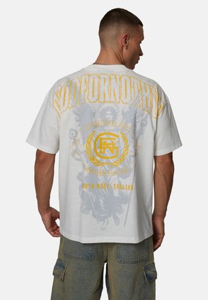 Biała, oversize koszulka z wyrazistymi żółtymi i szarymi grafikami na plecach, w tym tekstem, logo i skomplikowanymi wzorami.