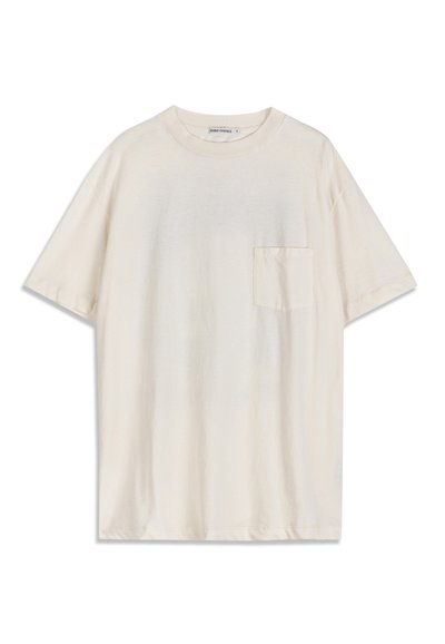 T-shirt à manches courtes de couleur crème avec un col rond et une petite poche poitrine sur le côté gauche, posé à plat sur un fond blanc.